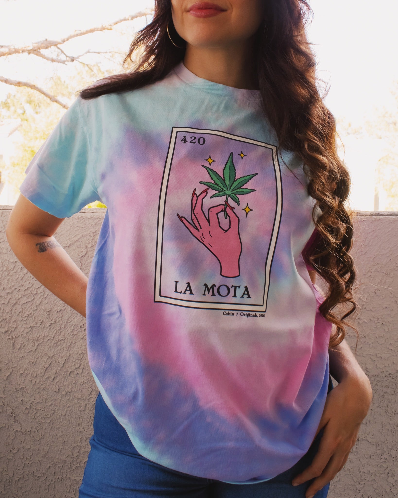 A pink, purple, and baby blue tie dye t-shirt with "La Mota" loteria card on the front. Cannabis shirts, stoner shirts, hippie girl apparel.