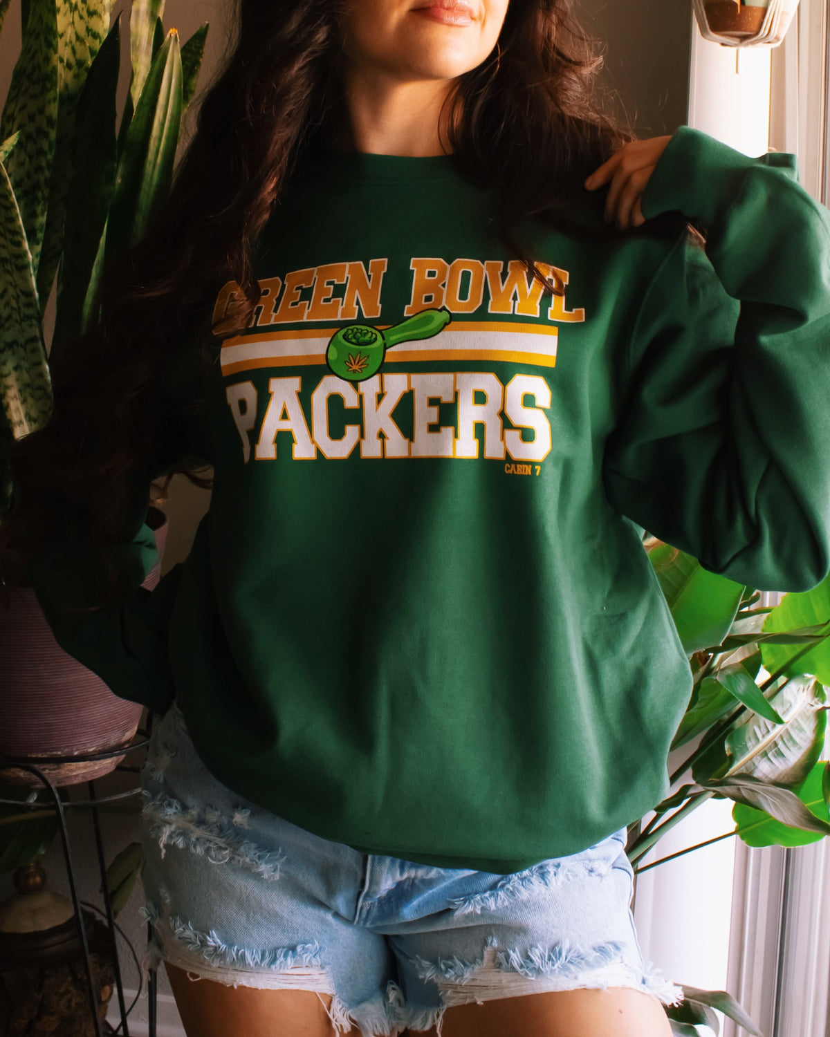 A dark green crewneck sweatshirt with 'GREEN BOWL PACKERS' printed in yellow and white with a green football graphic. Green Bay Packers stoner apparel, 420 apparel, hippie apparel.
