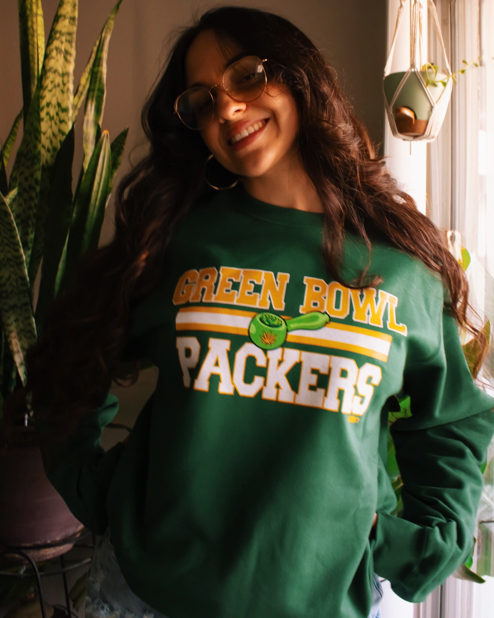 A dark green crewneck sweatshirt with 'GREEN BOWL PACKERS' printed in yellow and white with a green football graphic. Green Bay Packers stoner apparel, 420 apparel, hippie apparel.