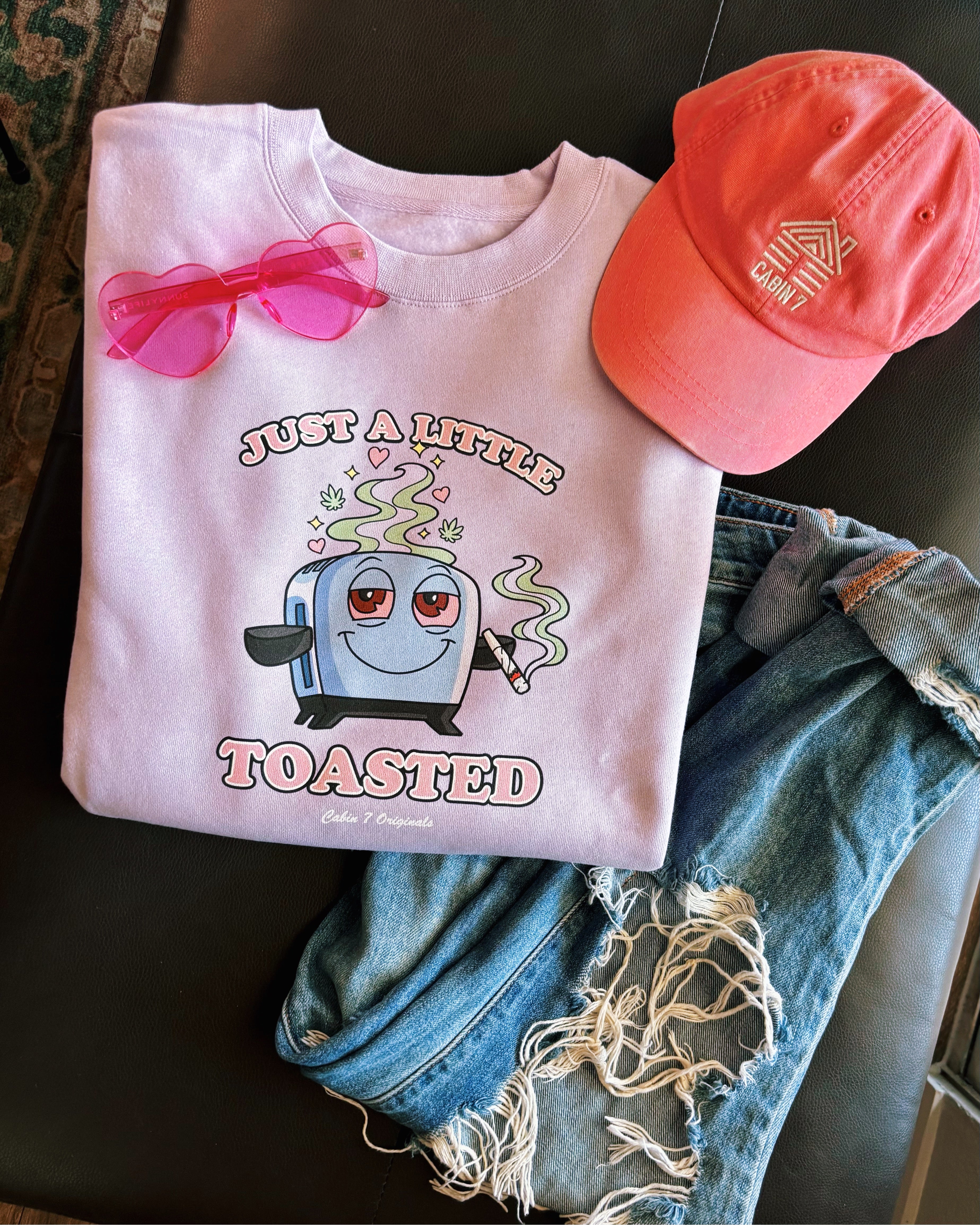 A light purple graphic T-shirt featuring a cartoon toaster with the text 'JUST A LITTLE TOASTED'.