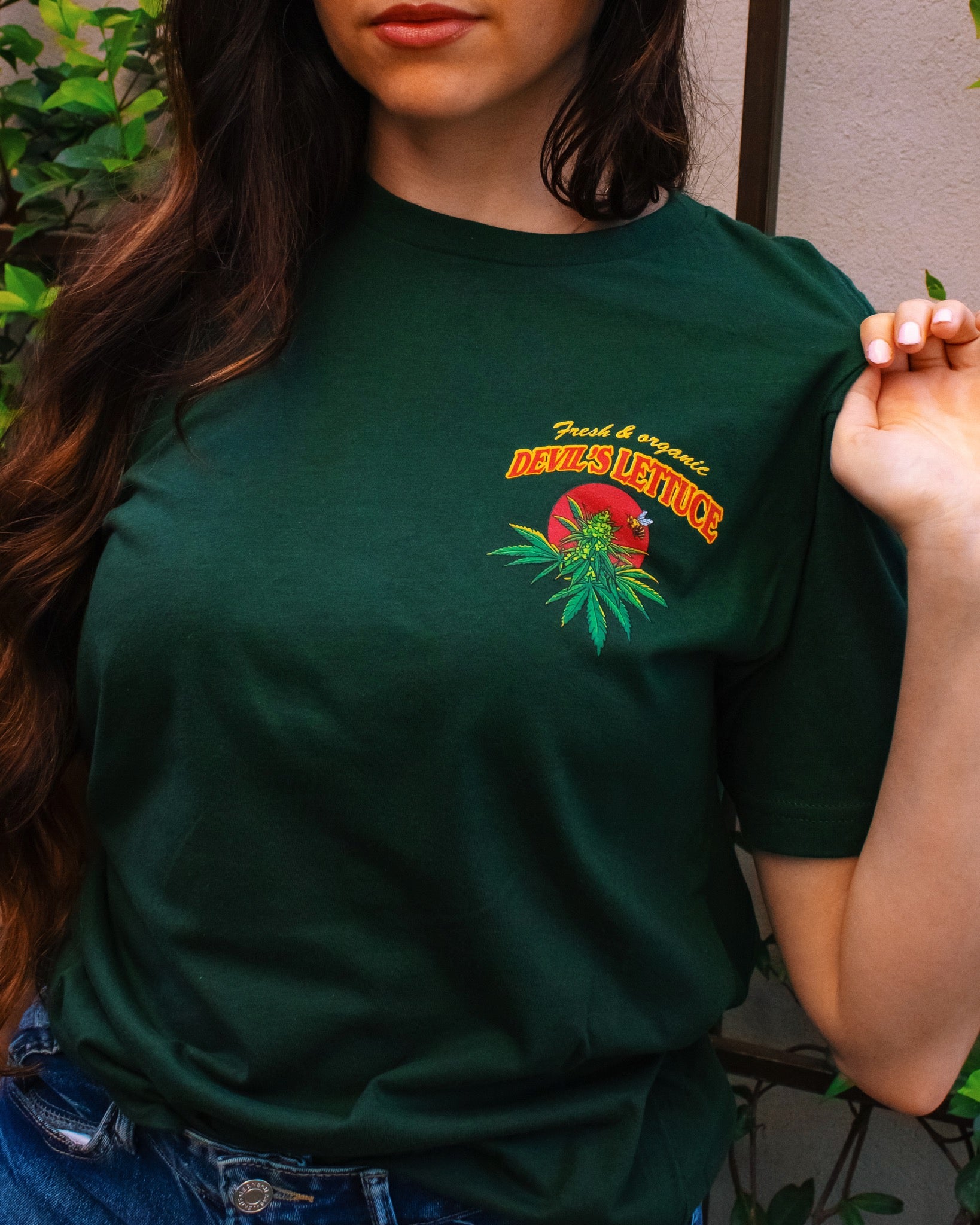 Person wearing a green Devil’s Lettuce t-shirt with a front left chest logo and text.