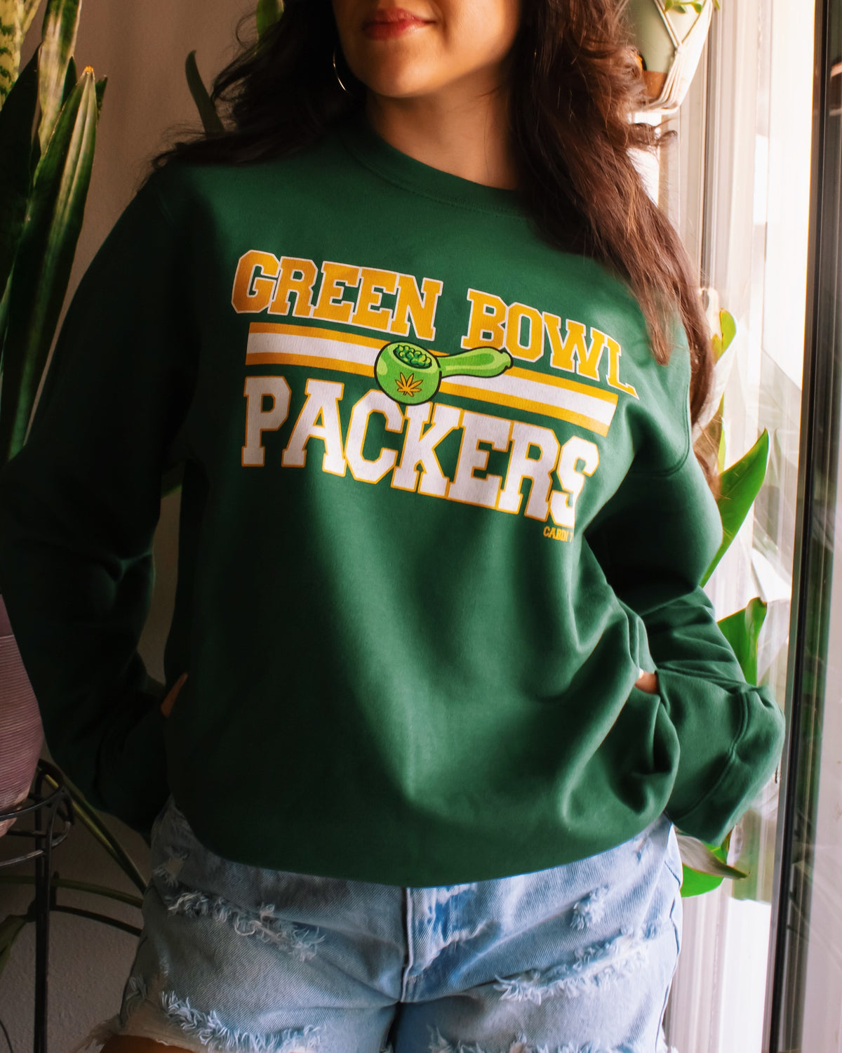 A dark green crewneck sweatshirt with 'GREEN BOWL PACKERS' printed in yellow and white with a green football graphic. Green Bay Packers stoner apparel, 420 apparel, hippie apparel.
