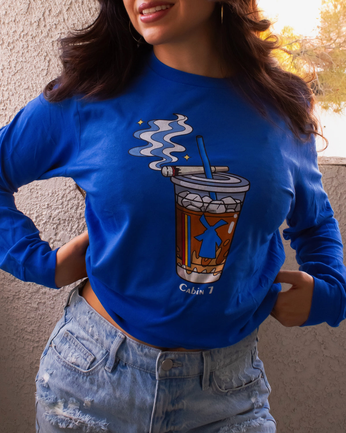 A cobalt blue graphic Dutchie Bros long sleeve shirt with graphic showing a Dutch Bros Coffee cup with smoke and the text 'Cabin 7'.
