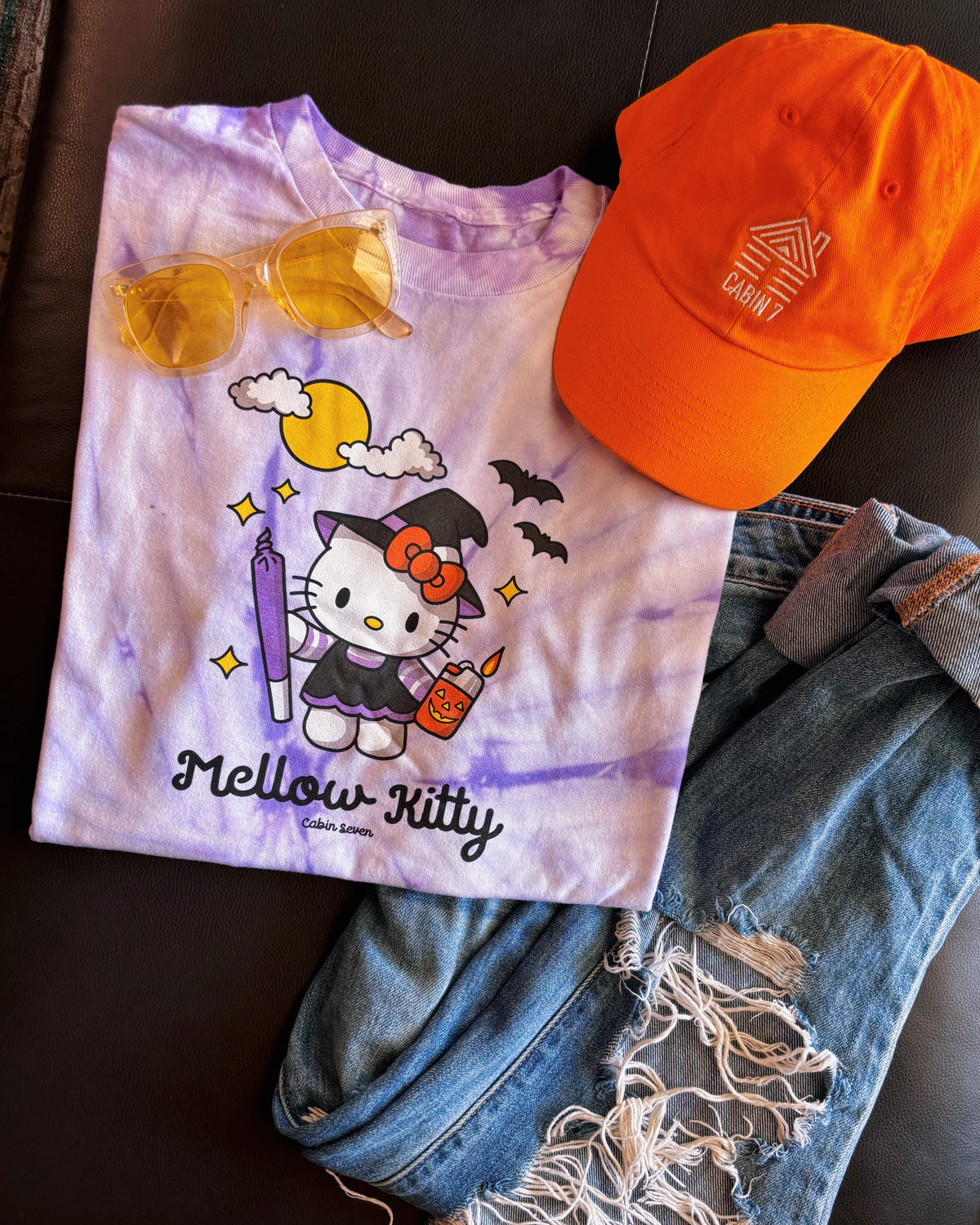 A purple tie-dye T-shirt featuring a Hello Kitty Halloween graphic with the text 'Mellow Kitty'.