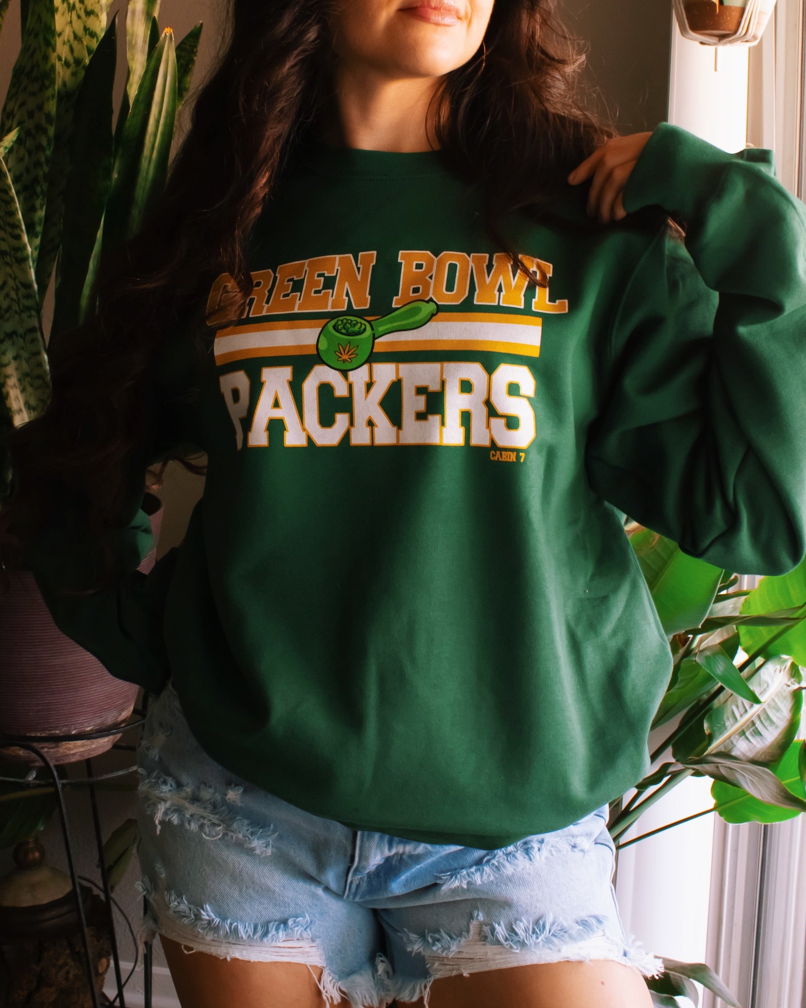 A dark green crewneck sweatshirt with 'GREEN BOWL PACKERS' printed in yellow and white with a green football graphic. Green Bay Packers stoner apparel, 420 apparel, hippie apparel.