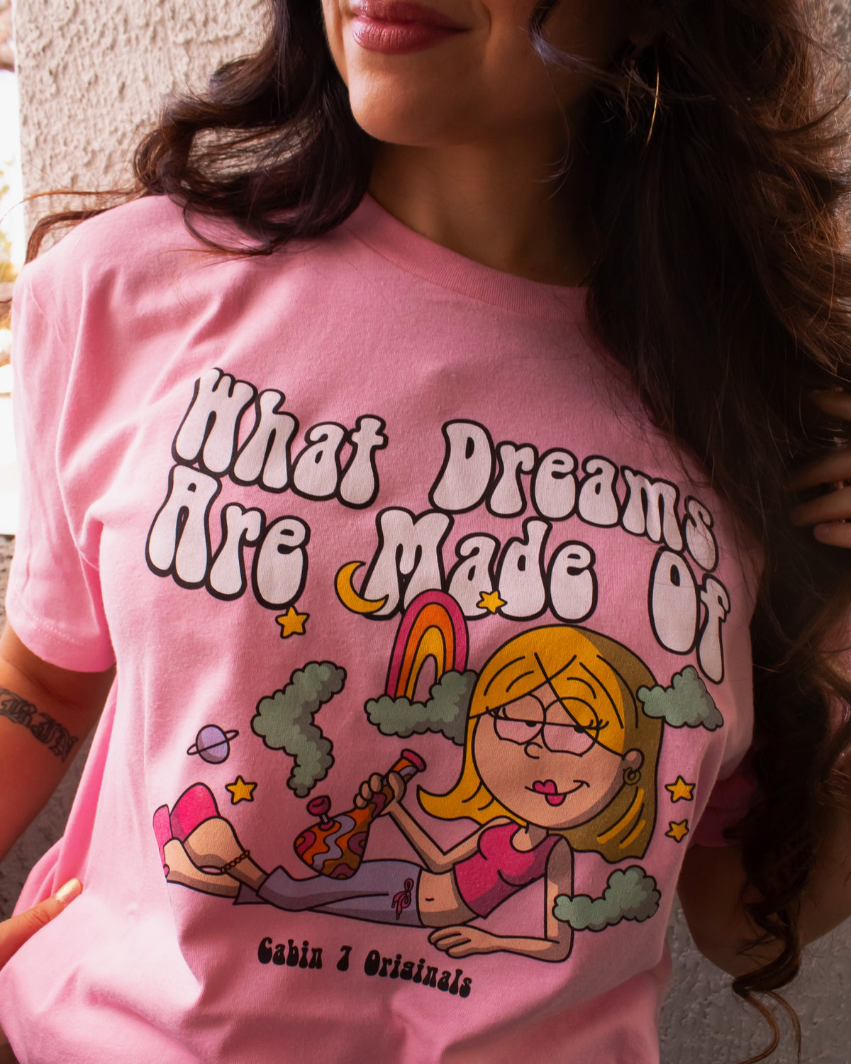 A pink t-shirt with a stoner Lizzie McGuire smoking a bong, that says "What Dreams Are Made Of".