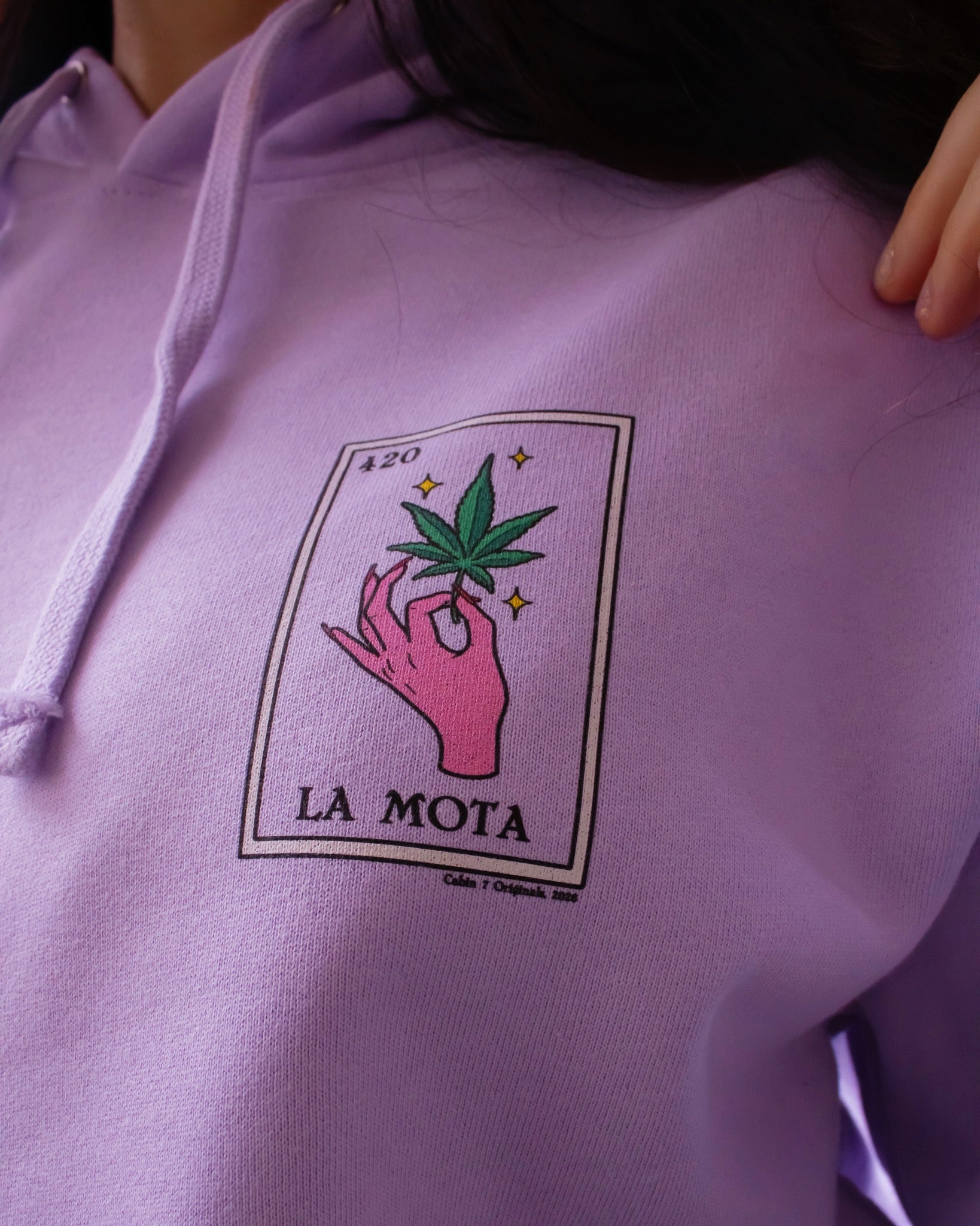 A light purple hoodie featuring a "La Mota" stoner loteria card on front. Stoner hoodie, stoner apparel, hippie apparel.