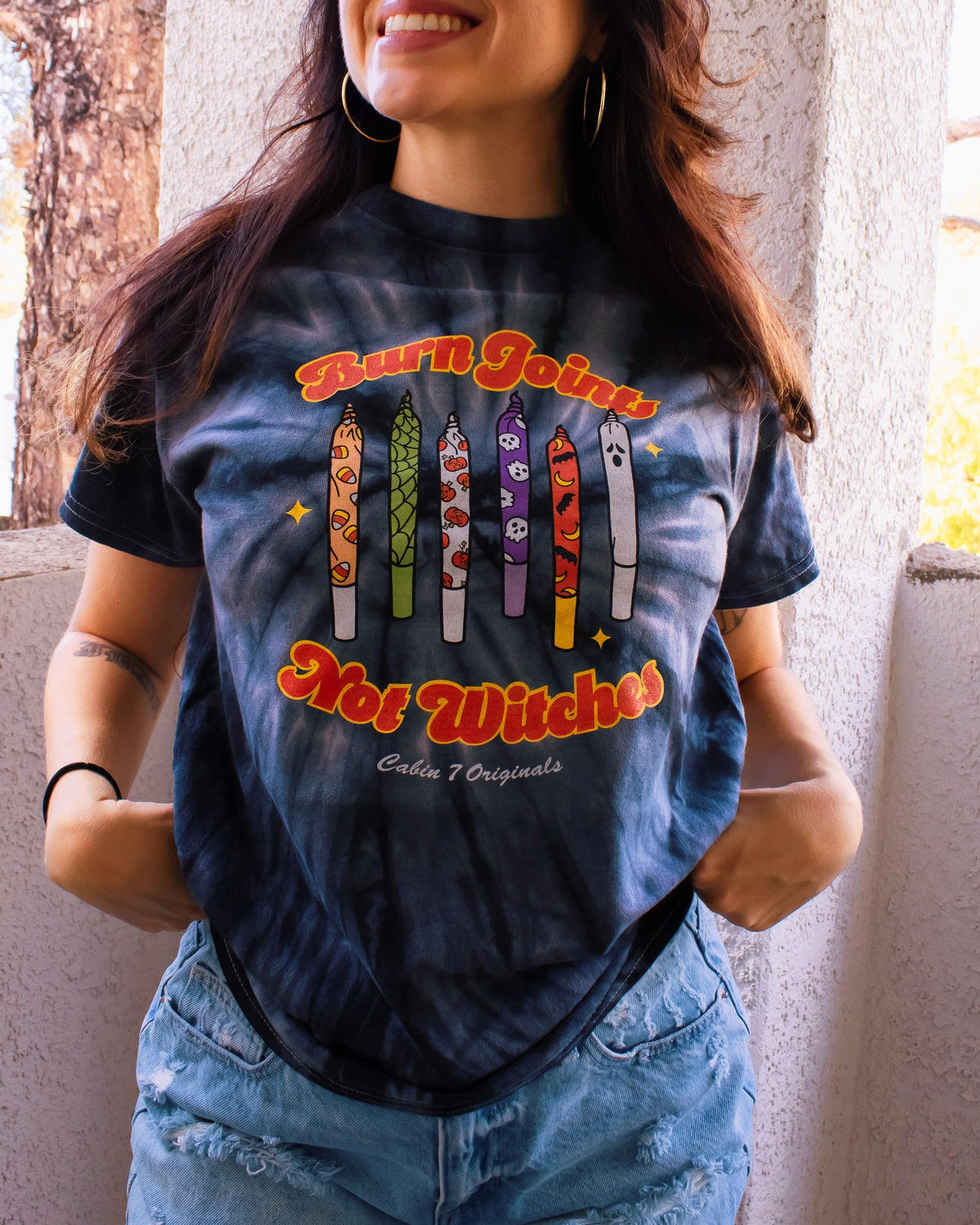 Black tie-dye shirt with colorful halloween design on front, featuring multiple spooky joints and the text "Burn Joints Not Witches".