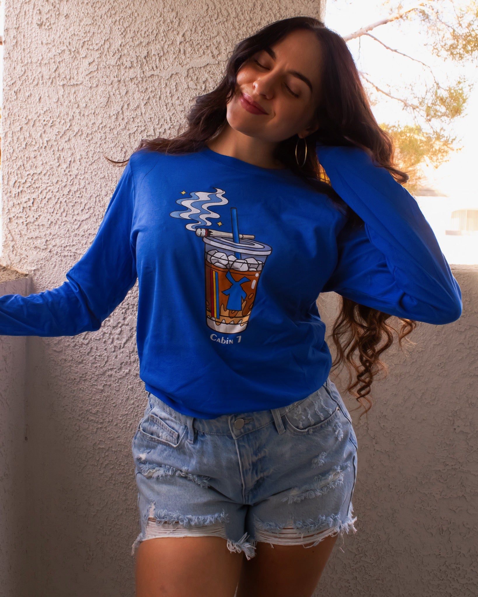 A cobalt blue graphic Dutchie Bros long sleeve shirt with graphic showing a Dutch Bros Coffee cup with smoke and the text 'Cabin 7'.