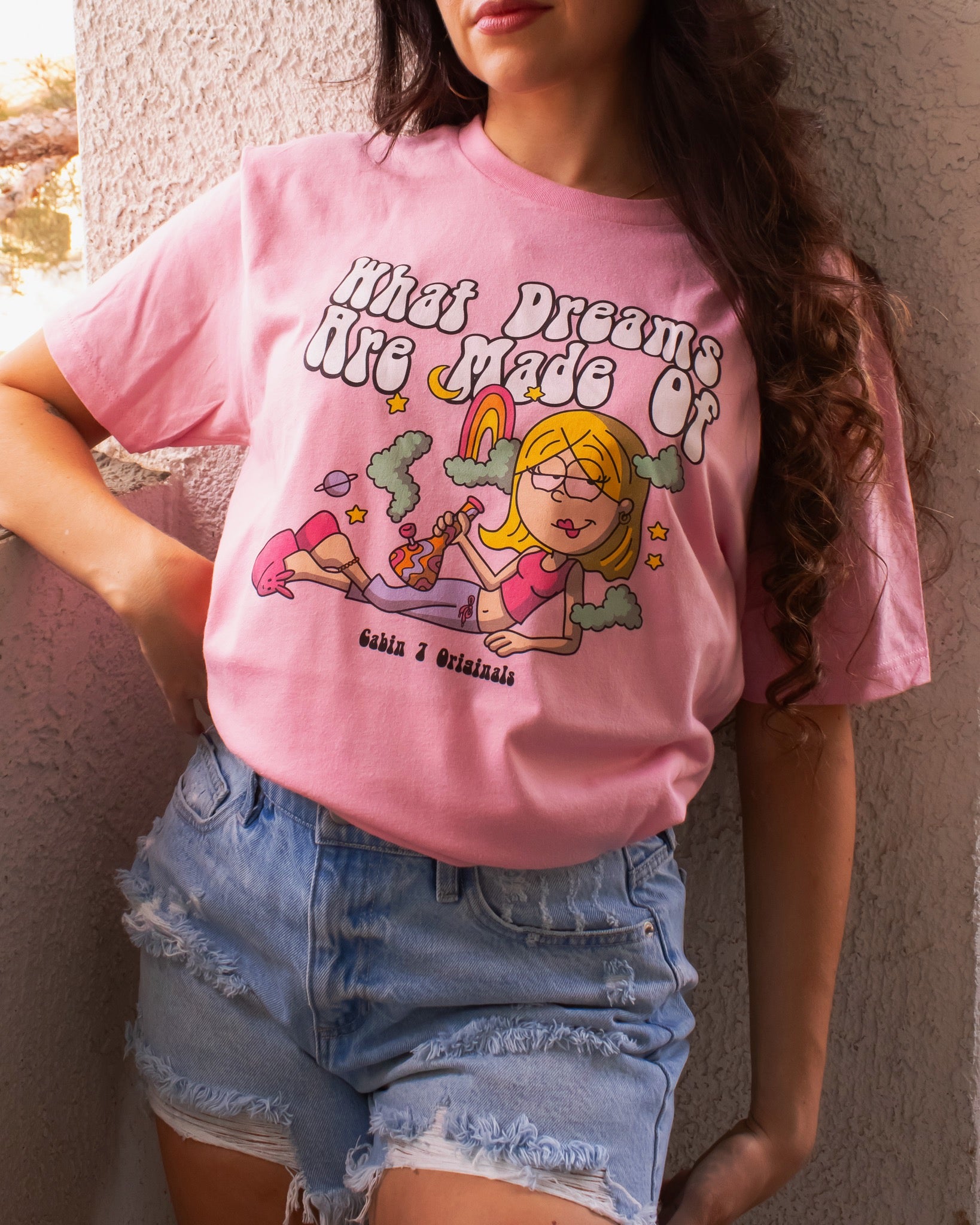 A pink t-shirt with a stoner Lizzie McGuire smoking a bong, that says "What Dreams Are Made Of".