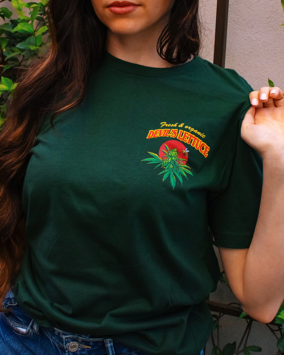 Person wearing a green Devil’s Lettuce t-shirt with a front left chest logo and text.