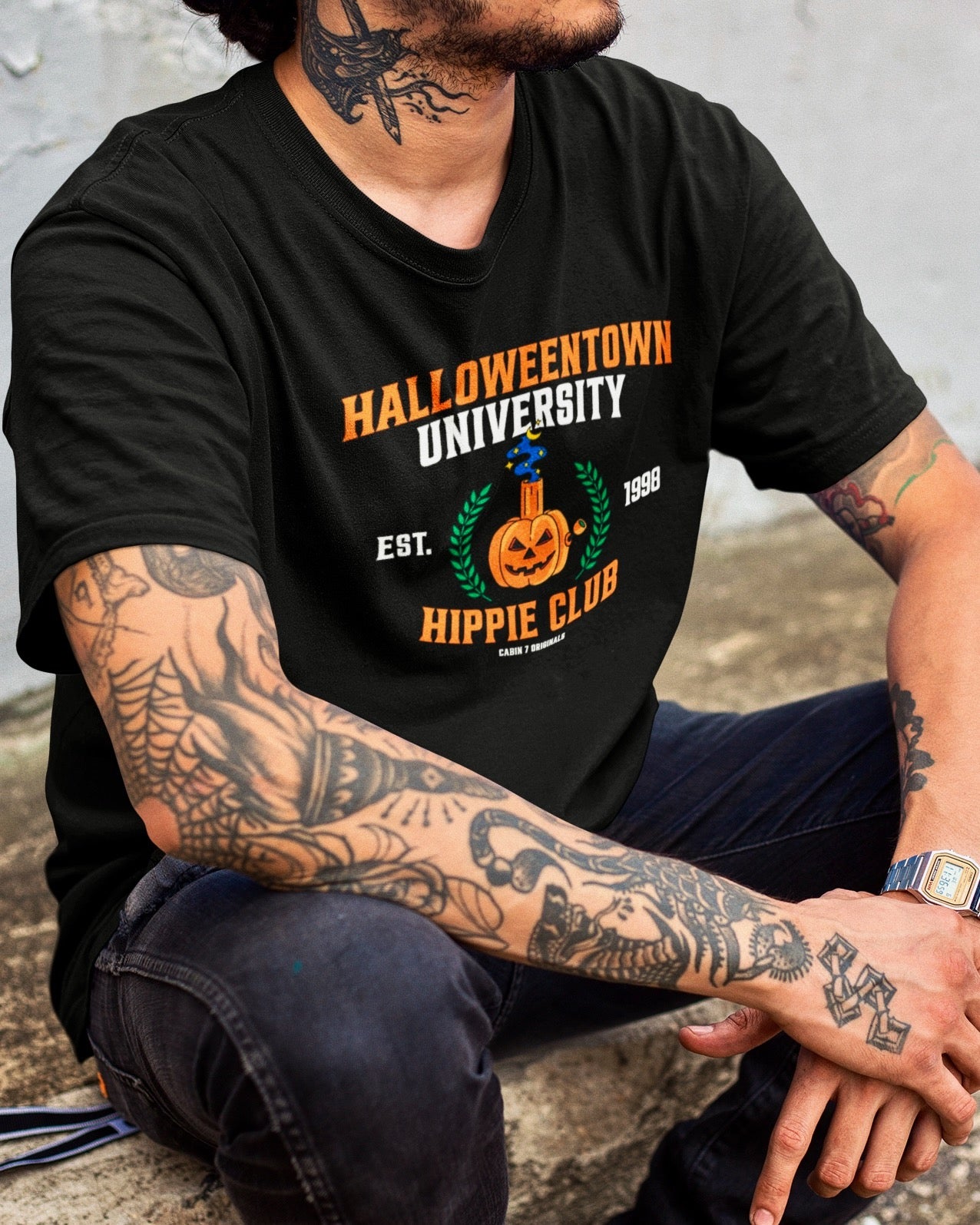 A black t-shirt with a stoner Halloween themed design that reads "Halloweentown University Hippie Club" and a pumpkin bong. Stoner shirts, Halloween apparel.