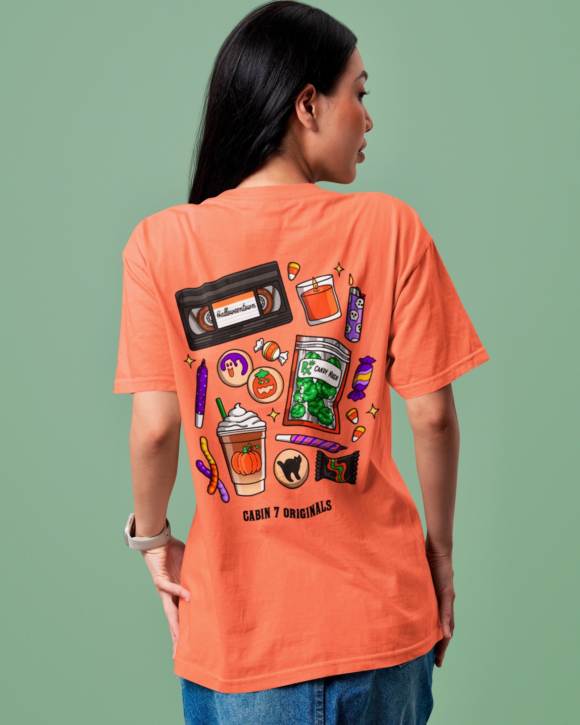 An orange t-shirt with a bright colorful stoner design, featuring several items such as a candle, a lighter, a VHS tape, and a bag of cannabis. 
