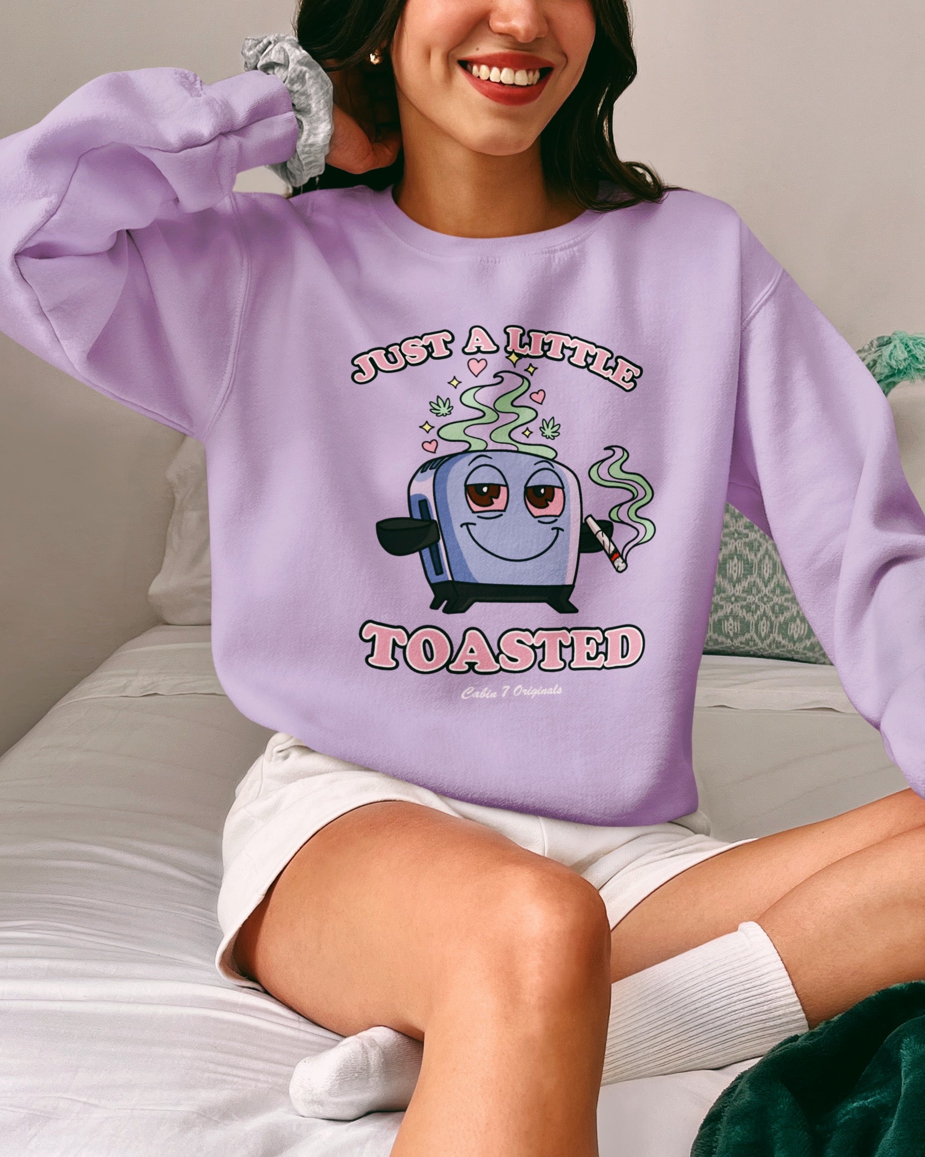 A light purple graphic T-shirt featuring a cartoon toaster with the text 'JUST A LITTLE TOASTED'.
