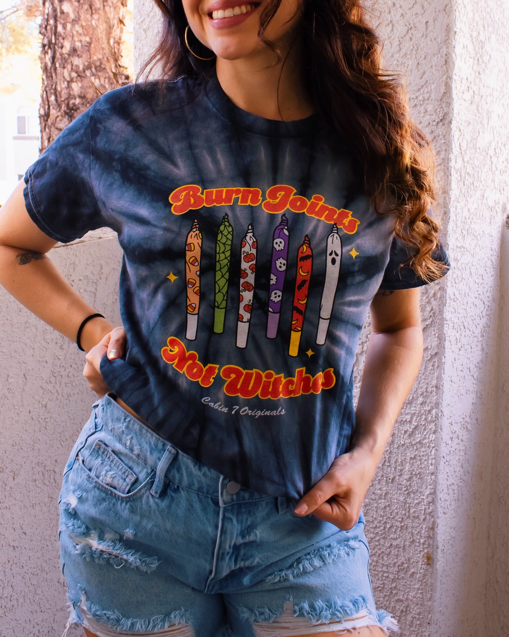 Black tie-dye shirt with colorful halloween design on front, featuring multiple spooky joints and the text "Burn Joints Not Witches".