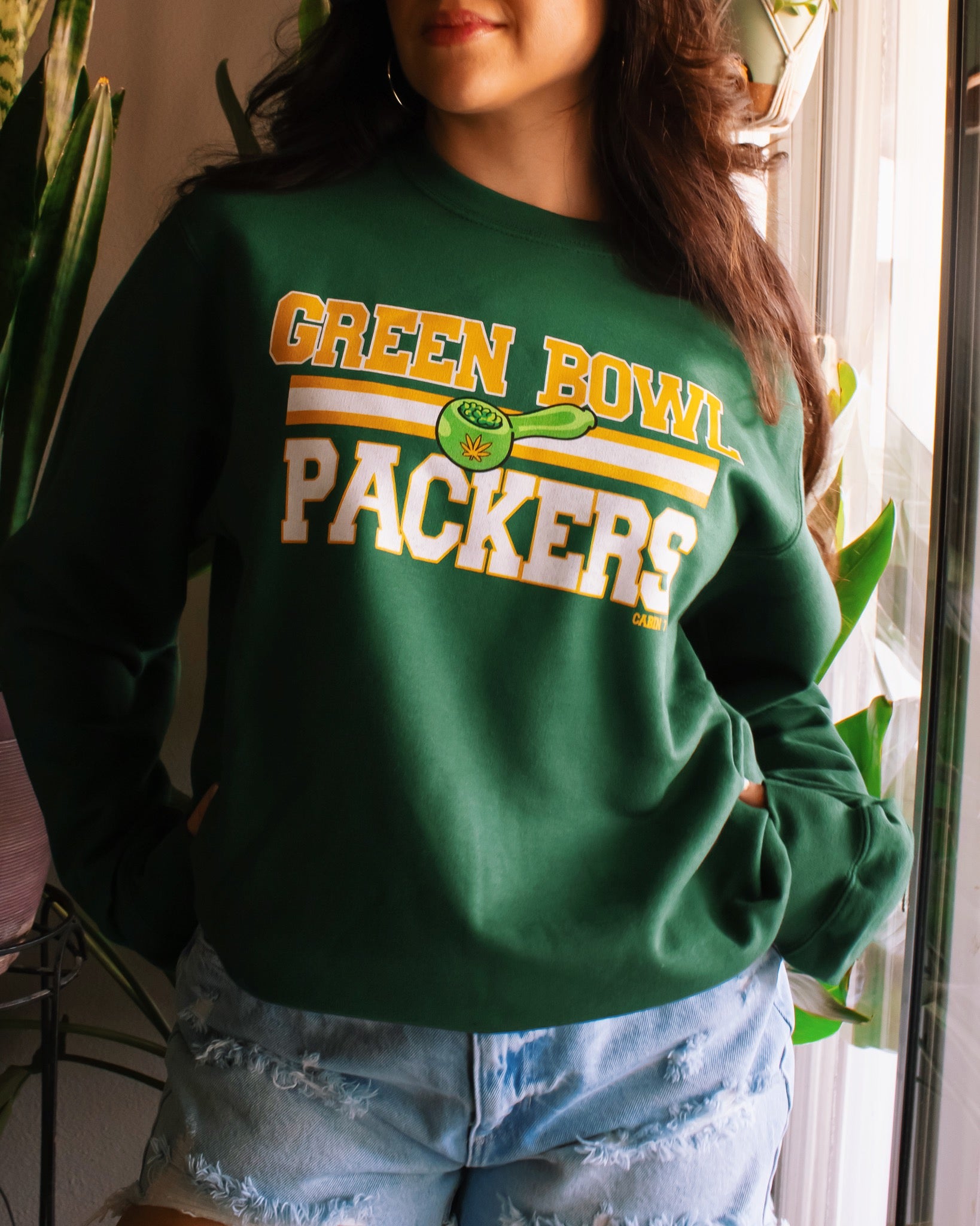A dark green crewneck sweatshirt with 'GREEN BOWL PACKERS' printed in yellow and white with a green football graphic. Green Bay Packers stoner apparel, 420 apparel, hippie apparel.