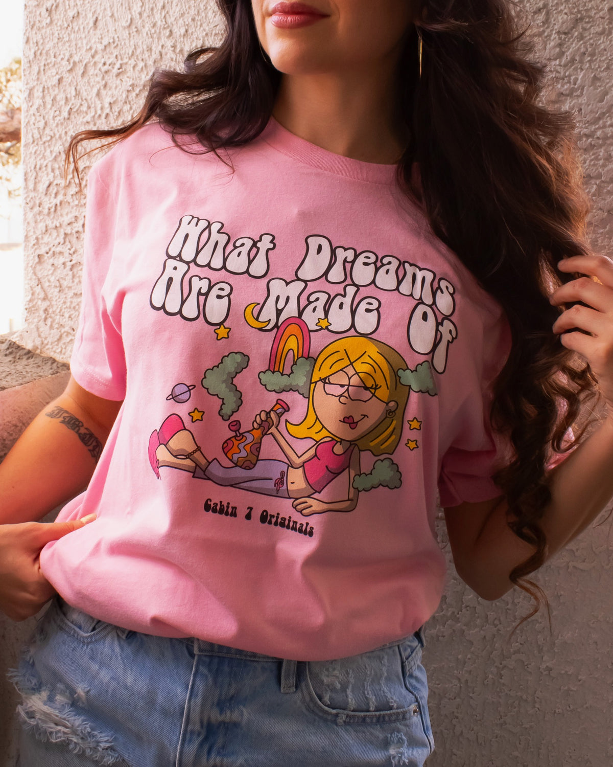 A pink t-shirt with a stoner Lizzie McGuire smoking a bong, that says "What Dreams Are Made Of".