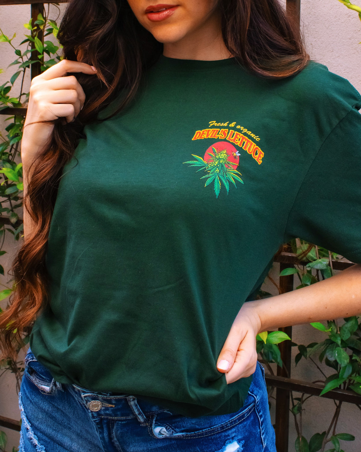 Front view of person wearing a green Devil’s Lettuce t-shirt with a left chest logo and text.